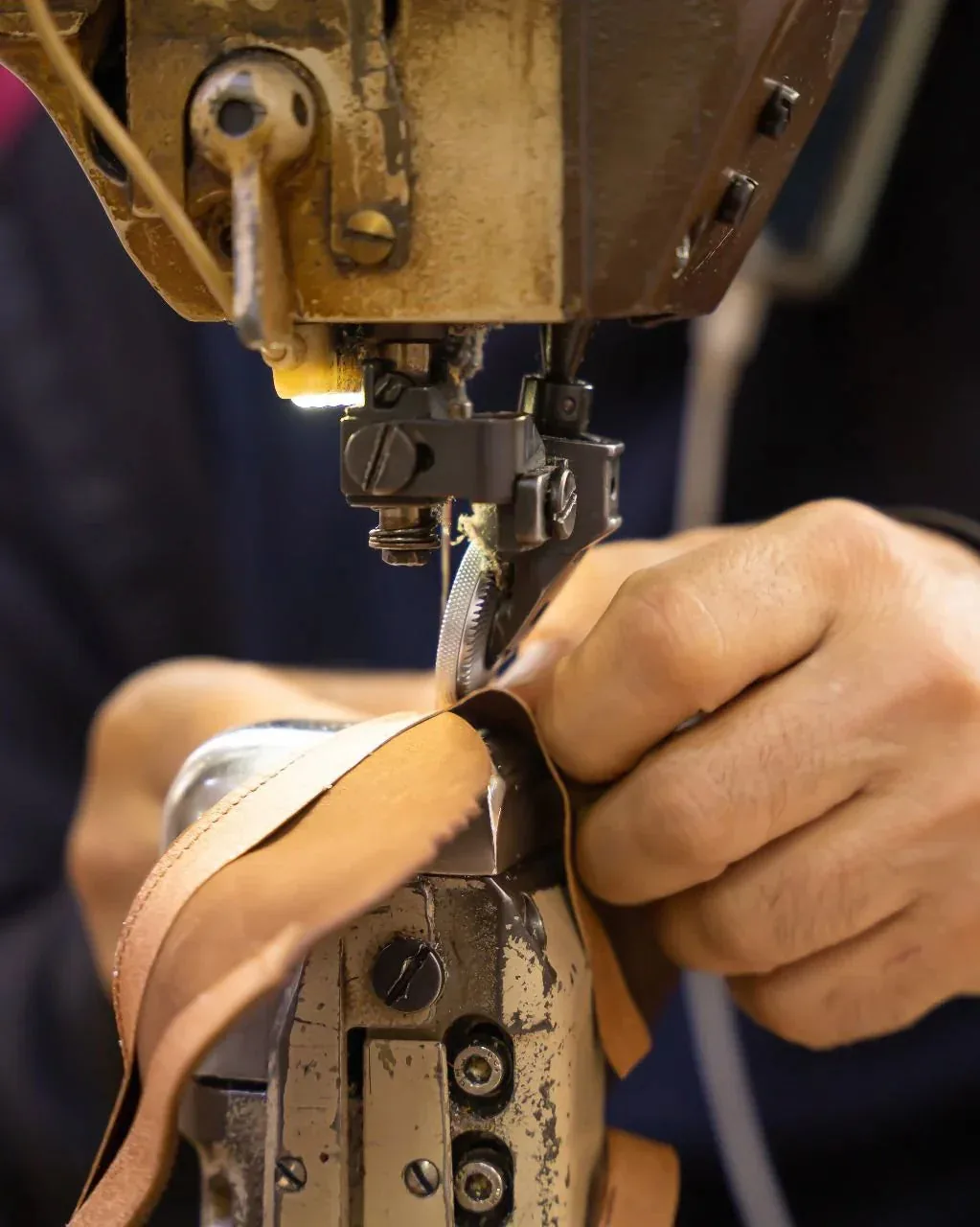 Official THUNA craftsmanship image showing leather stitching at a sewing machine
