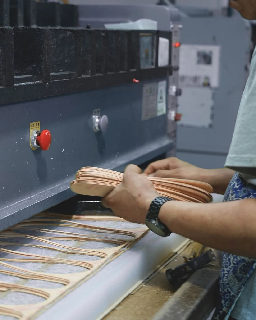 Worker handling layered outsole components during footwear production